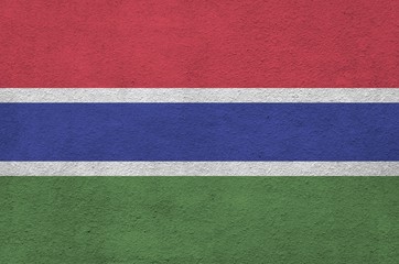 Gambia flag depicted in bright paint colors on old relief plastering wall. Textured banner on rough...