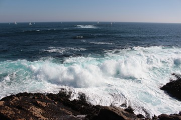 Fototapeta premium Movement on the shore. A view of sea waves bursting on the rocks and forming foam in Algarrobo beach in Chile