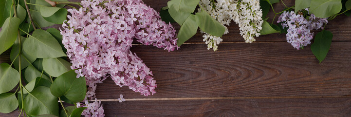 Plate and decor of flowers on the background of vintage wooden planks.Vintage background with lilac flowers and place under the text. View from above. Flat lay. Cutlery. Banner.