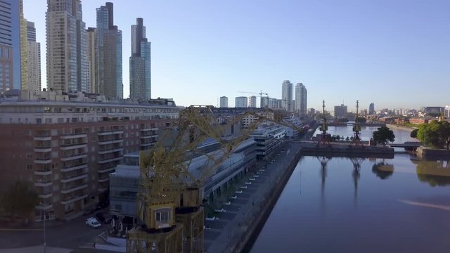 Aerial rising revealing Puerto Madero cityscape behind loading cranes