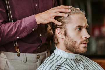 Fototapeta premium barber putting hands on hear of handsome bearded man