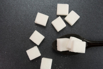 Selective focus of sugar cubes on spoon. Illness and diabetes concept.