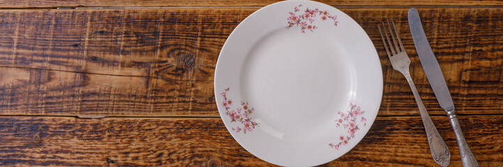 Plate and cutlery on the background of vintage wooden boards. Vintage background and space for text. View from above. Flat lay. Cutlery. Banner.