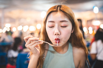 Traveler Asian blogger women travel in Bangkok, Thailand, beautiful female using Women travel in Thailand concept.Woman enjoy her bowl of noodles in outdoor night market in Bangkok city