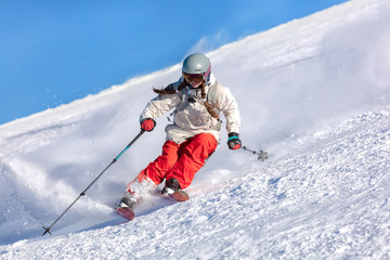 Girl On the Ski. a skier in a bright suit and outfit with long pigtails on her head rides on the...