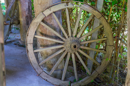 Antique wooden wagon wheel with metal rim standing upright in the garage.