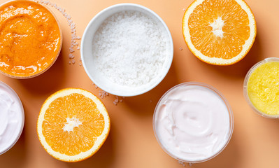 White skin cream, salt, scrub and oranges on a beige background, top view, banner. Body and skin care concept. Homemade cosmetics, ingredients for homemade scrub.