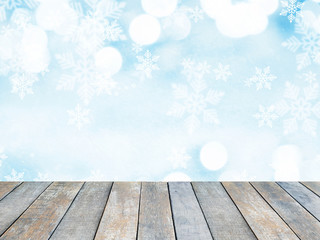 Wooden table top over abstract Christmas blue background with white snowflakes and bokeh.