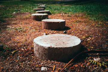 Closeup of round stone pathway on vibrant ground with fallen leaves. Selective focus. Copy space.