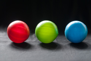 Red green blue plastic balls with black fabric background