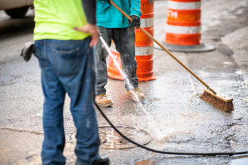 Road workers cleaning the street with water