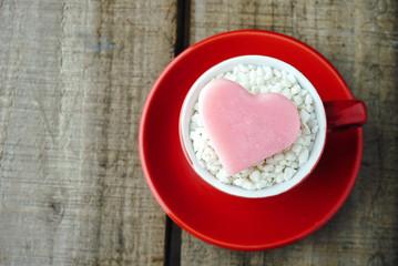 Topview pink heart shape on red coffee cup with wood table background ,vintage love concept.