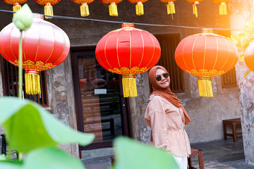Obraz na płótnie Canvas Confident muslim Woman tourist look at the chinese traditional lantern hanging at outdoor in the evening, Travel concept. Chinese theme.