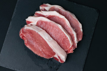 sliced ​​pieces of fresh meat on a black board