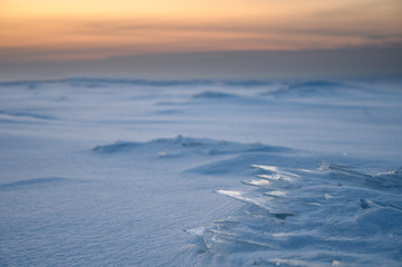 Ice plates on the surface of a frozen bay at sunset.
