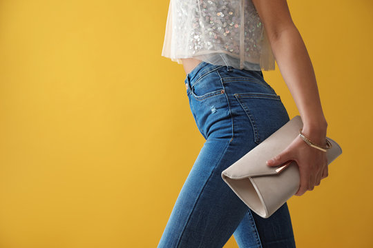 Woman In Jeans With Clutch Purse On Yellow Background, Closeup. Space For Text