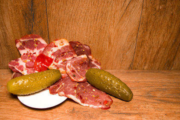 Cured meat appetizer. Pickled Cucumber. Old wood background.