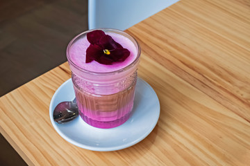 Coffee latte with colorful foam on the wooden table.