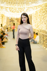 Fototapeta premium A cheerful Asian woman enjoys taking photo with light bokeh background decoration for the Christmas festival and new year celebration.