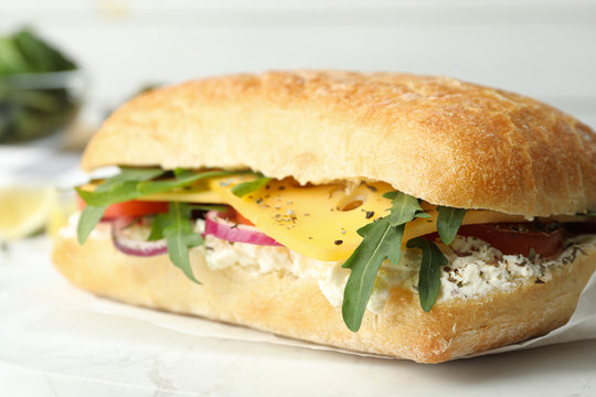 Delicious sandwich with fresh vegetables and cheese on white table, closeup