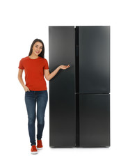 Young woman near refrigerator on white background
