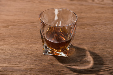 Glass of brandy with shadow on wooden table