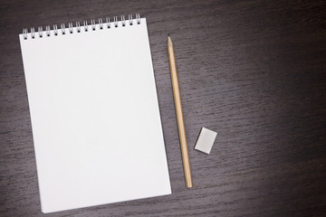 Mock up, top view. The notebook is clean, empty lies on the table. Minimalism. Dark wooden background.