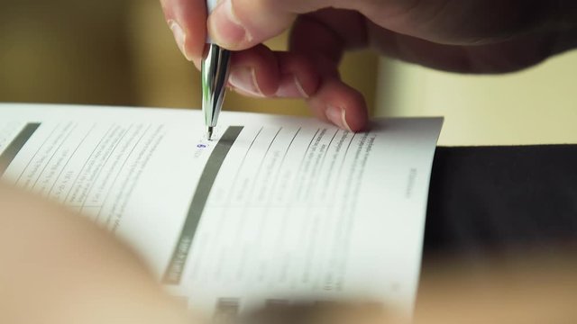 Close up shot, hand testing doing examination test with standardized test form and answers bubbled, filling out answers.