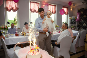 Baby girl 1 year old eating birthday cake in room. Birthday party. Childhood
