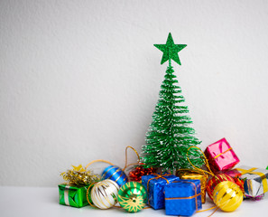 Green Christmas tree with colourful gift boxes and little beautiful ball on the wood table and white background