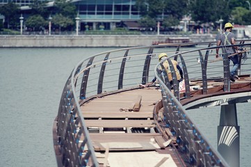 Worker are working together to repair wood bridge over the river.