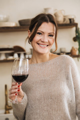 Smiling young woman holding wineglass while standing