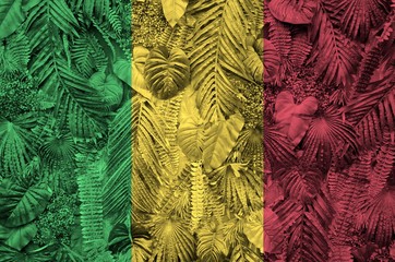 Mali flag depicted on many leafs of monstera palm trees. Trendy fashionable backdrop