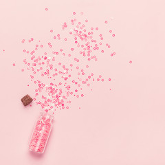 Pink Confetti Bottle and scattering of shining stars on pink background. Festive background