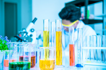 Test tubes and solution beakers in a science laboratory with a multicolored liquid on the laboratory table for a chemical background Concept Search
