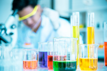 Test tubes and solution beakers in a science laboratory with a multicolored liquid on the laboratory table for a chemical background Concept Search