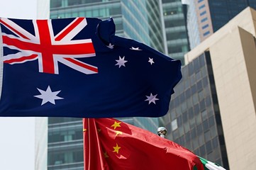 Australia flag and china waving in the wind against high building background together. Diplomacy concept, international relations.