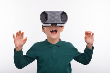 Photo of amazed little boy wearing VR helmet