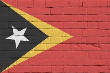 Timor Leste flag depicted in paint colors on old brick wall. Textured banner on big brick wall...