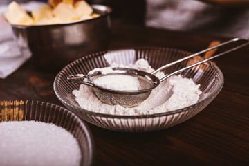 Fototapeta na wymiar Bowl of flour with sieve among ingredients