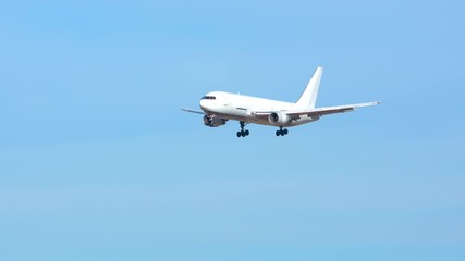 Generic Air Cargo Freighter Airplane Flying in a Blue Sky over Mountains during Final Approach on a Sunny Day