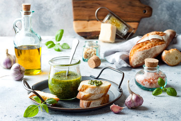 Pesto sauce in glass jar with ingredients.. Basil, olive oil, parmesan, garlic, pine nuts.