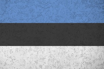 Estonia flag depicted in bright paint colors on old relief plastering wall. Textured banner on...