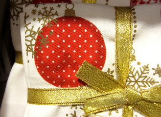 Christmas cotton napkin with a pattern of Christmas baubleand stars wrapped in gold ribbon.