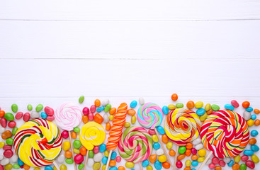 Colorful lollipops and different colored round candy on white background
