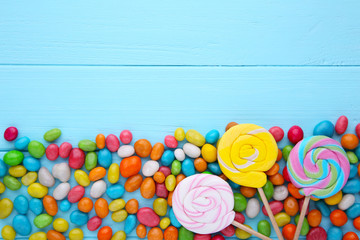 Fototapeta na wymiar Colorful lollipops and different colored round candy on blue background