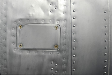 Details of some aluminum panels riveted together to make up the fuselage of a plane.