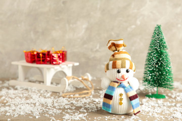 Small snowman with white sleigh and christmas tree on grey background