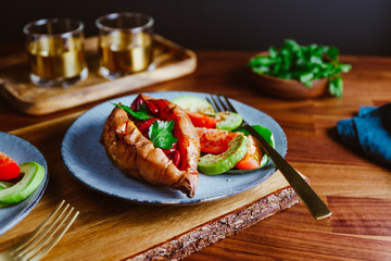 Baked sweet potato filled with red beans stewed in tomato paste served with avocado and cherry tomatoes on a plate. Healthy veggie recipe.