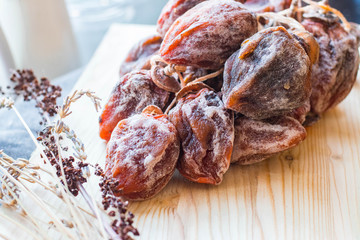 Dried sweet persimmon on wooden board with natural sugar layer. Vegan dessert.